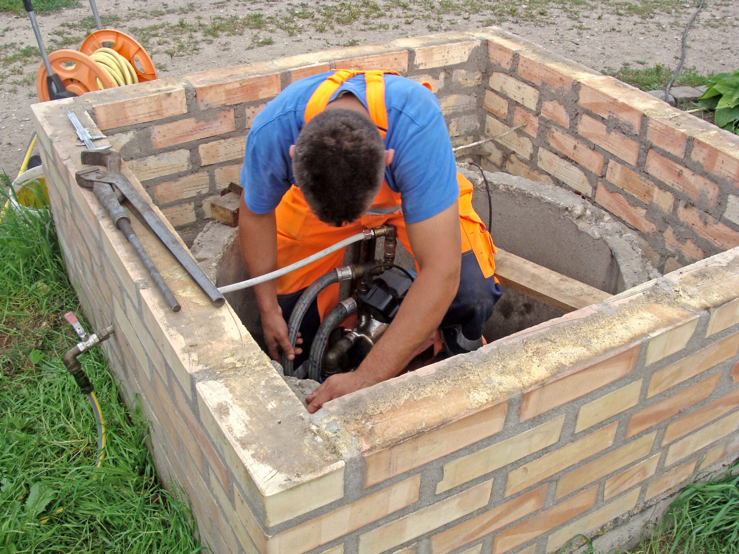 Plumber is Working in Opened Well Repairing Water Pump